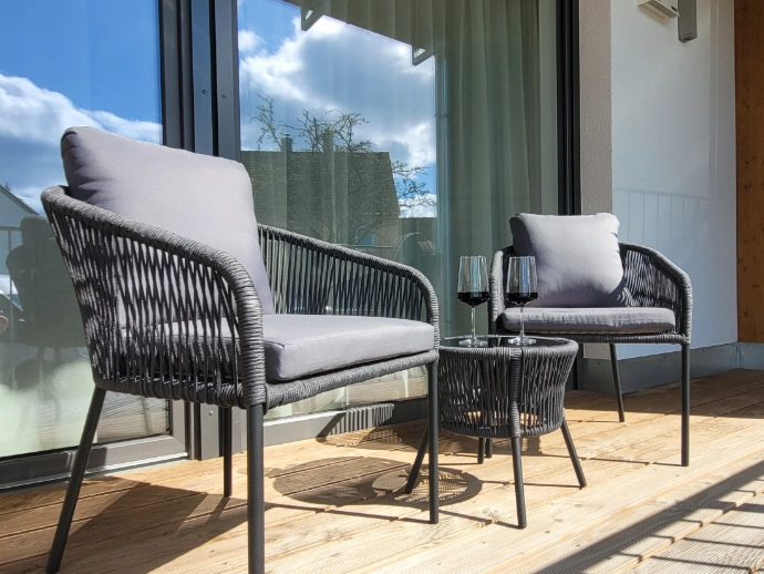 Outdoormöbel auf Balkon mit zwei Gläsern Wein im Sonnenschein